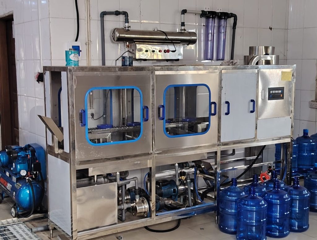 QGF-120 automatic 5-gallon water filling machine beside filled 19-litre water barrels.